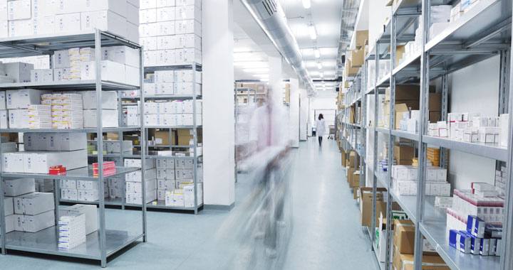 Almacén farmacéutico con estantería de medicamentos y un operador en movimiento